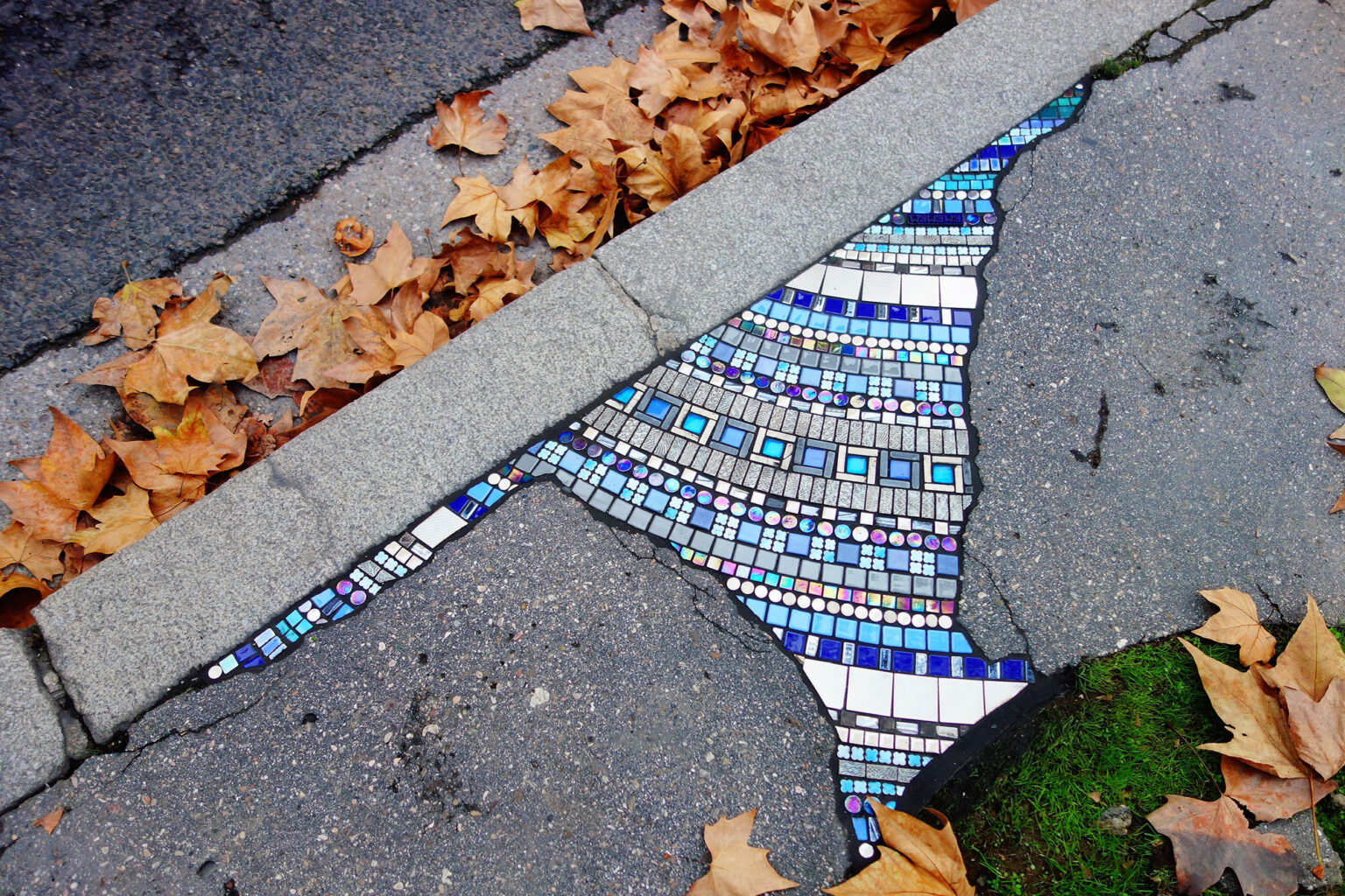 Ulični umetnik keramičkim mozaikom krpi oštećene fasade i trotoar
